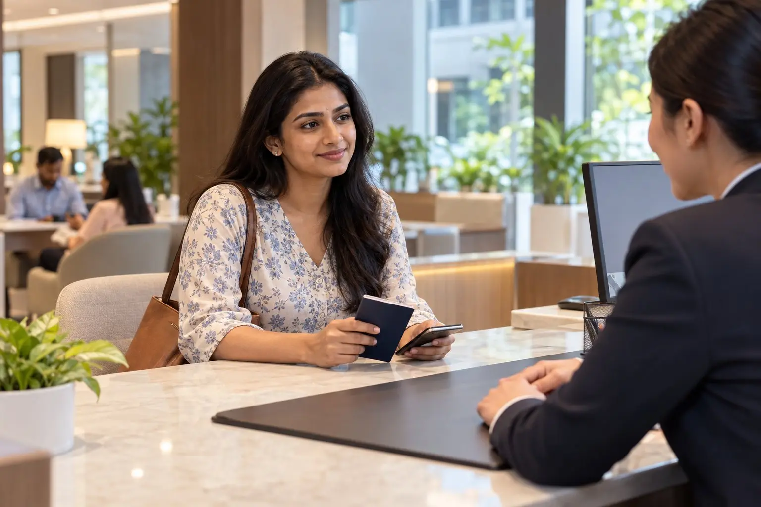 A newcomer setting up a bank account at a bright counter with documents and a phone